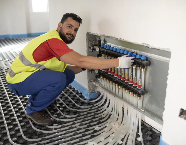 Un technicien, en train d'installer un plancher chauffant près de Quettehou dans la Manche