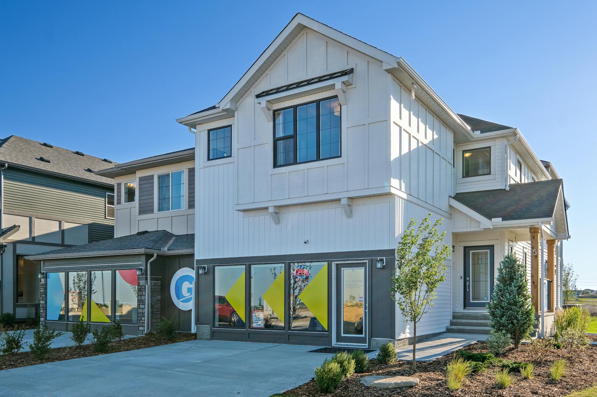 White showhome with landscaped front yard, under a blue sky