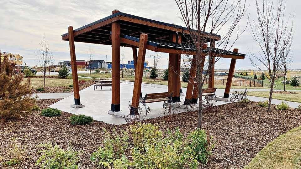 Wooden sitting area surrounded by mulch and freshly-planted trees.
