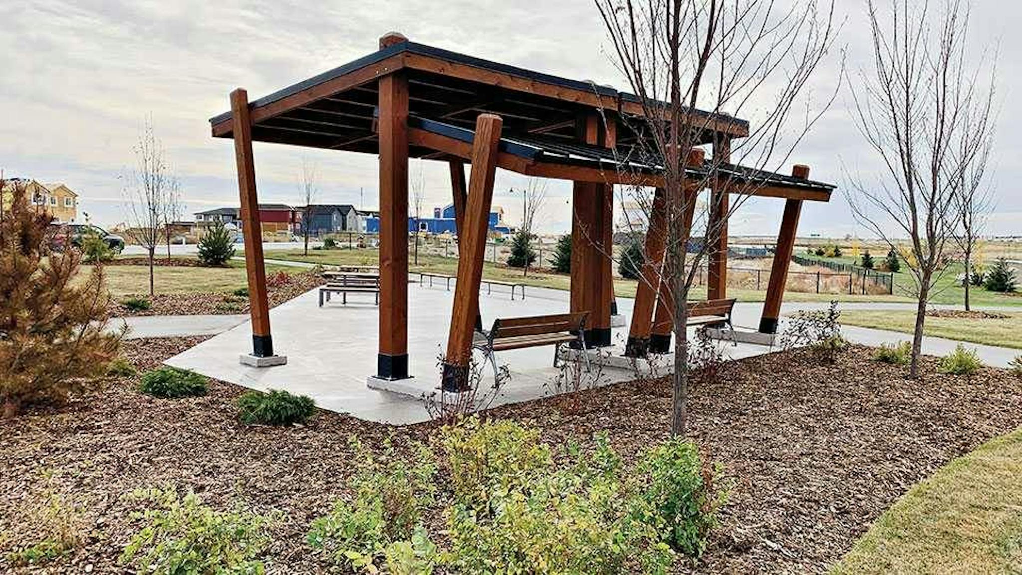 Wooden sitting area surrounded by mulch and freshly-planted trees.