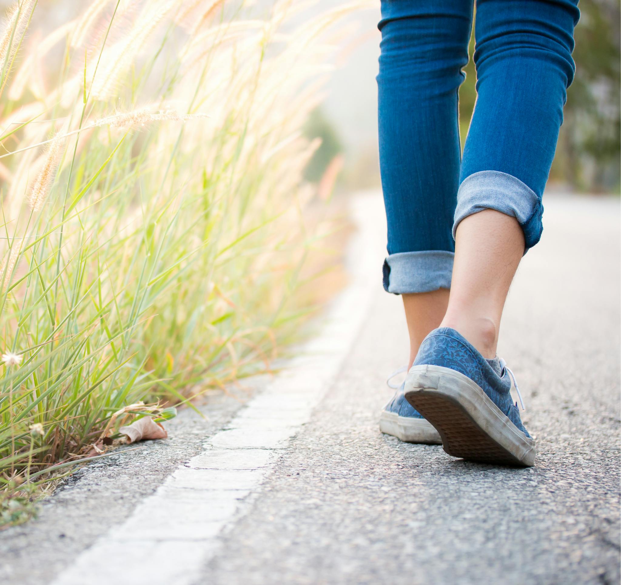 Stock photo of feet walking on an asphalt footpath