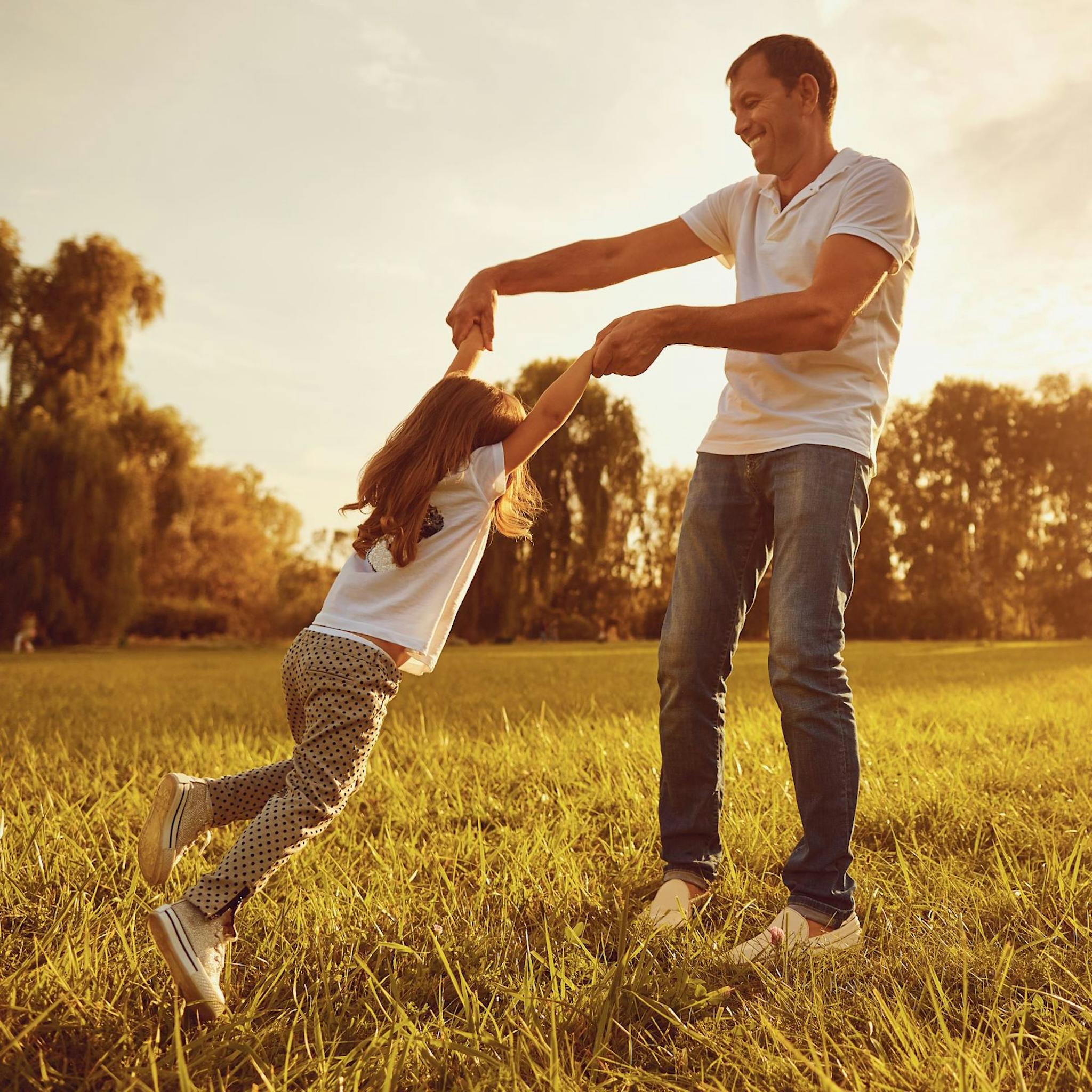 Father and daughter playing together in a golden field.