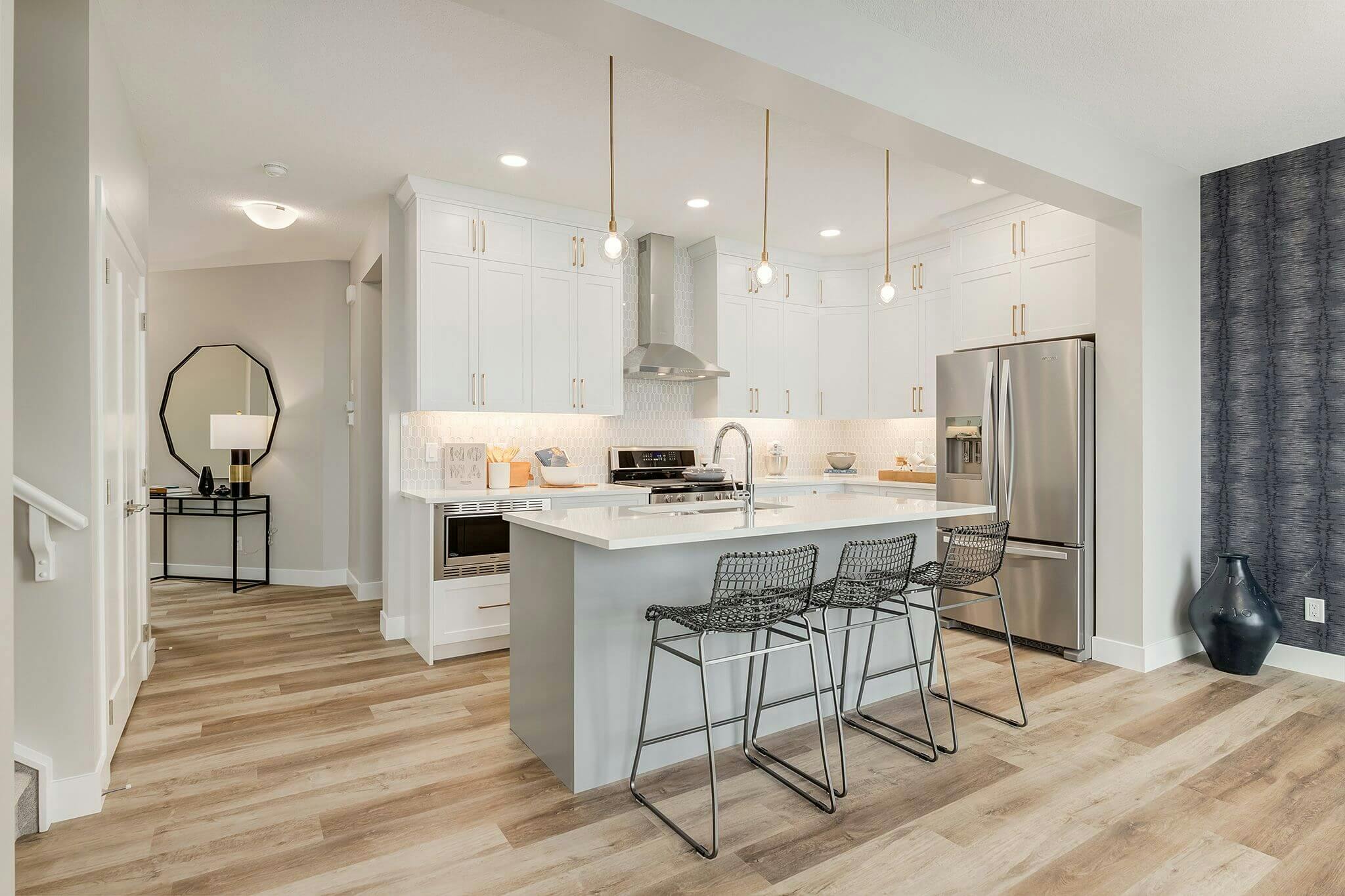 Brightly-lit kitchen interior with hanging lights and metal bar chairs.
