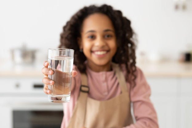 Young Girl Smiling as She Drinks Water