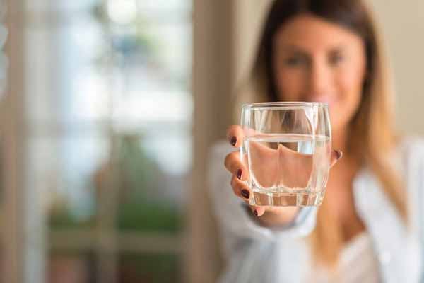 Lợi ích sức khỏe của việc uống nước sạch Ảnh Người phụ nữ cầm ly