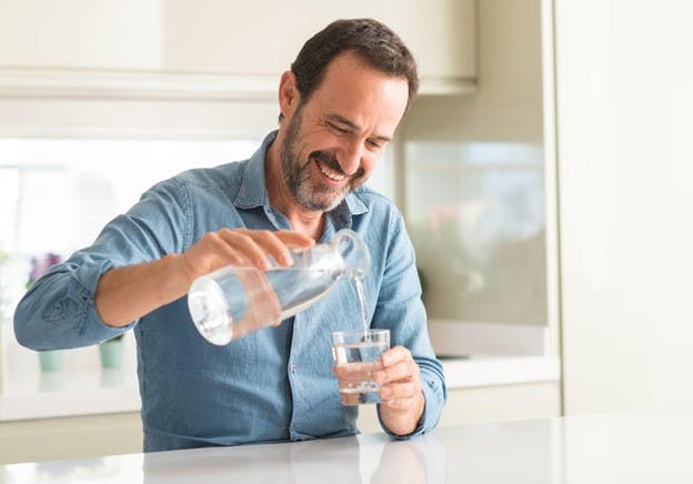 Man Happy at Home Pours Fresh Glass of Conditioned Water