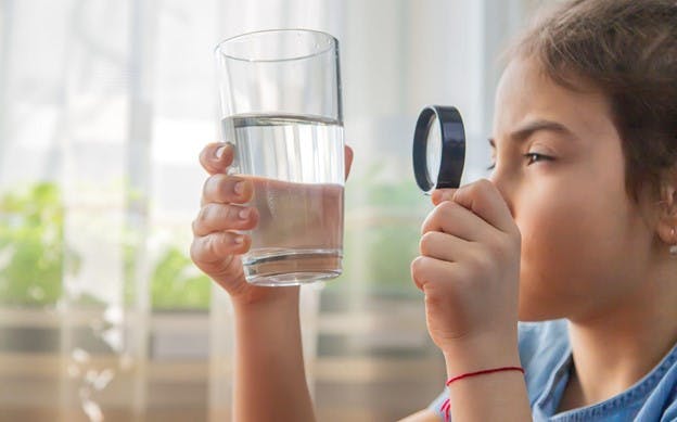 Water Filtration Systems Child Examines Results of Filter on Water