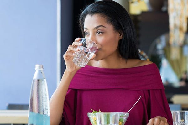 Woman Drinking Fresh Filtered Water From Bottle in Kitchen