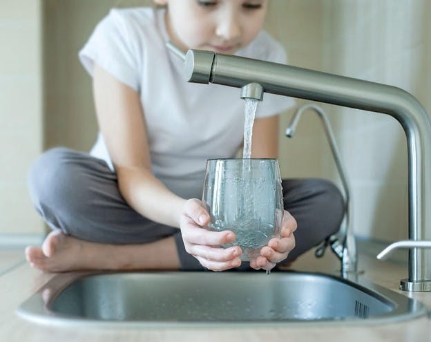 Advanced Water Filtration Technology at Home Child Pours Water