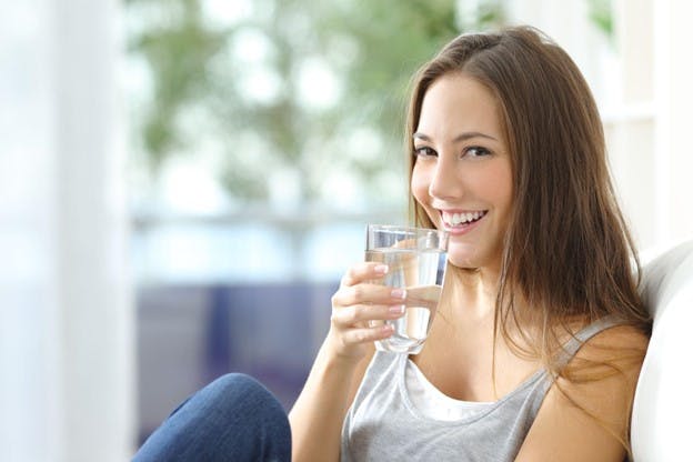 Woman Smiles With Fresh Glass of Drinking Water