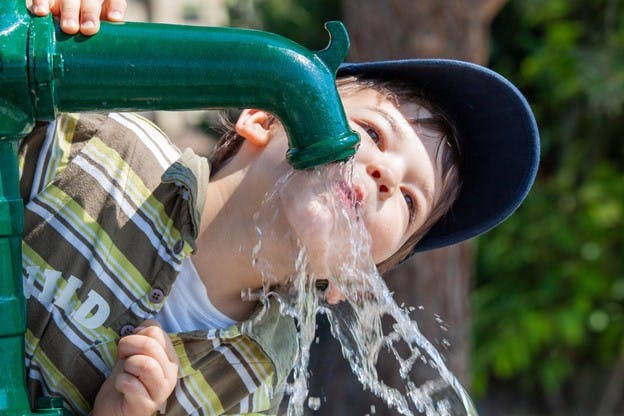 Private Well Water Image of Child Drinking from Outside Faucet