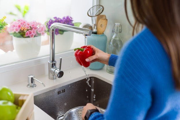 Woman Washes Vegetables Under Sink