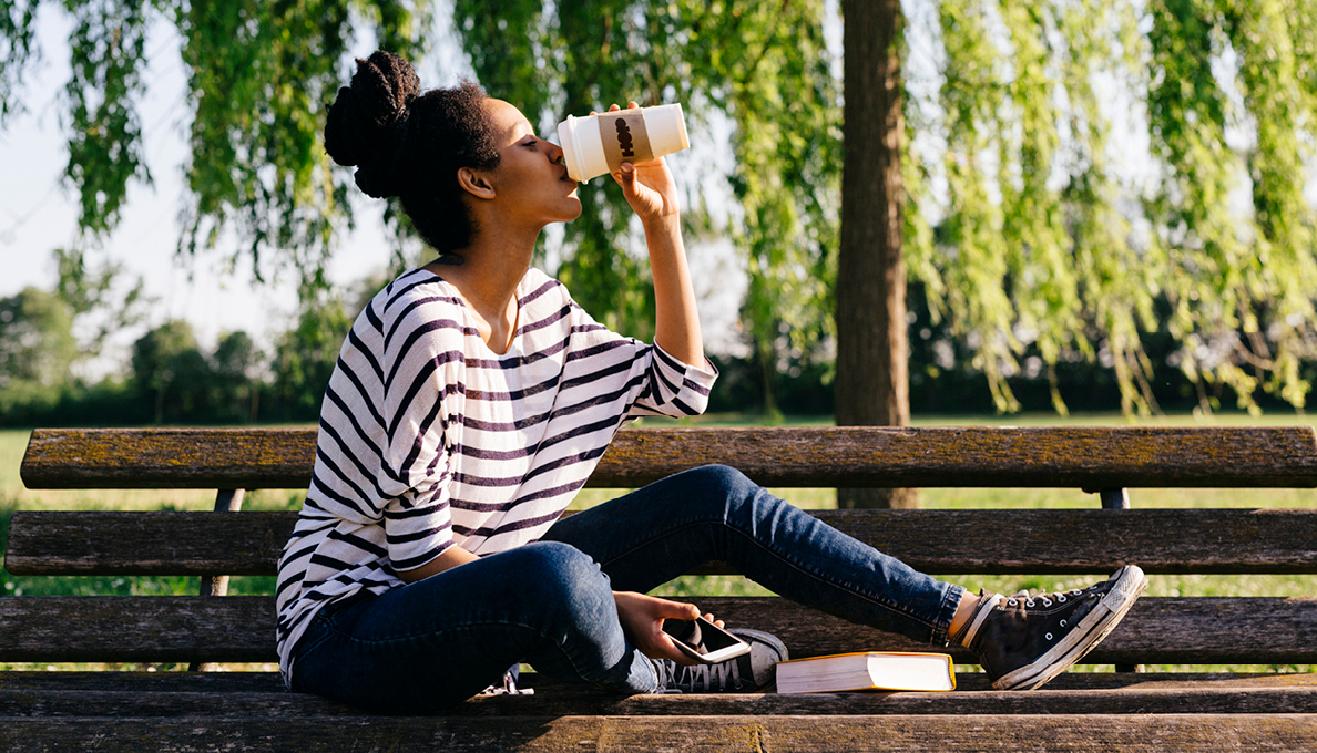 Woman on bench drinking coffee