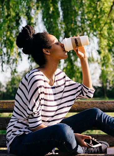 Woman on bench drinking coffee