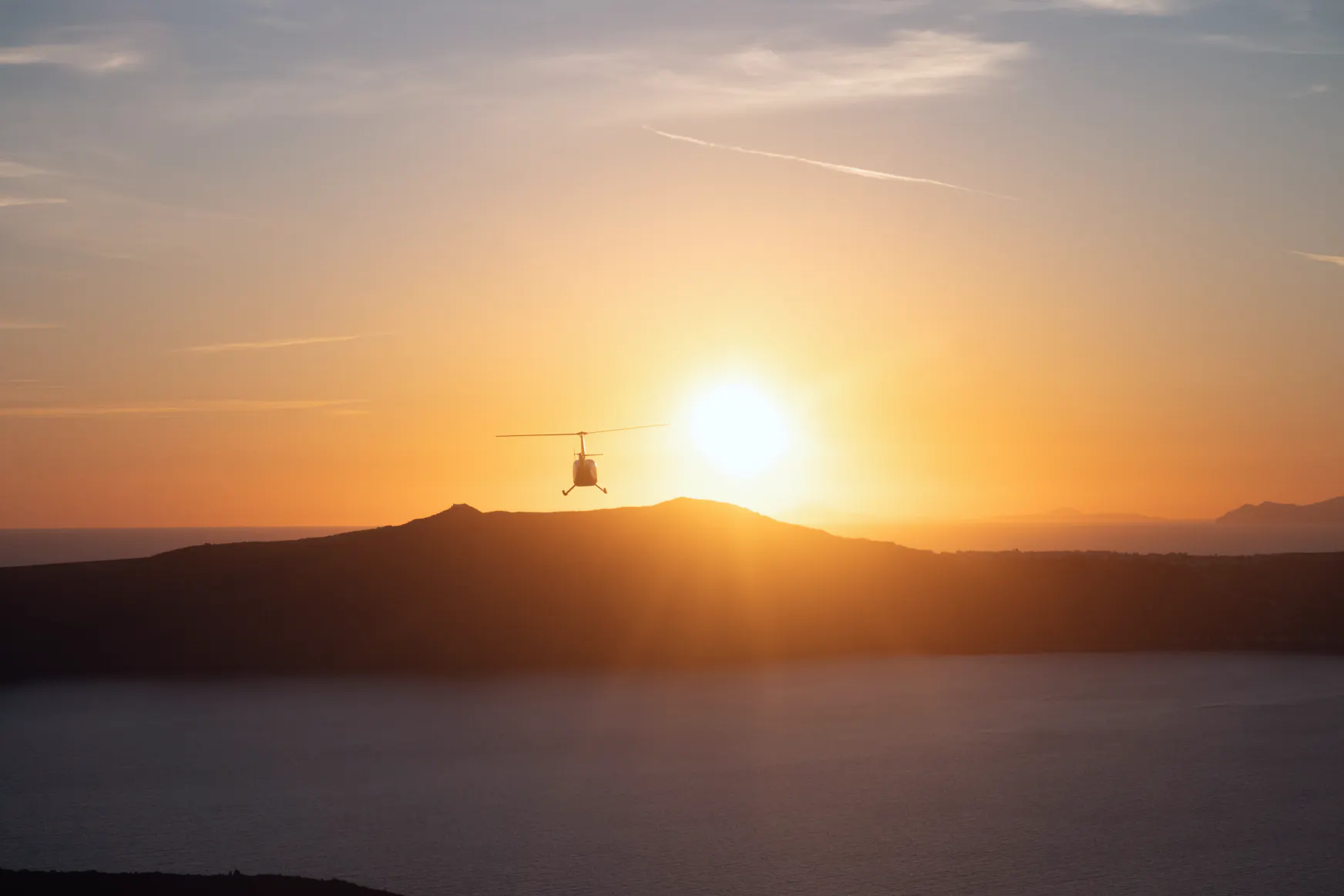 What's the best thing to do in Santorini? Helicopter flying over Santorini facing the sun set.