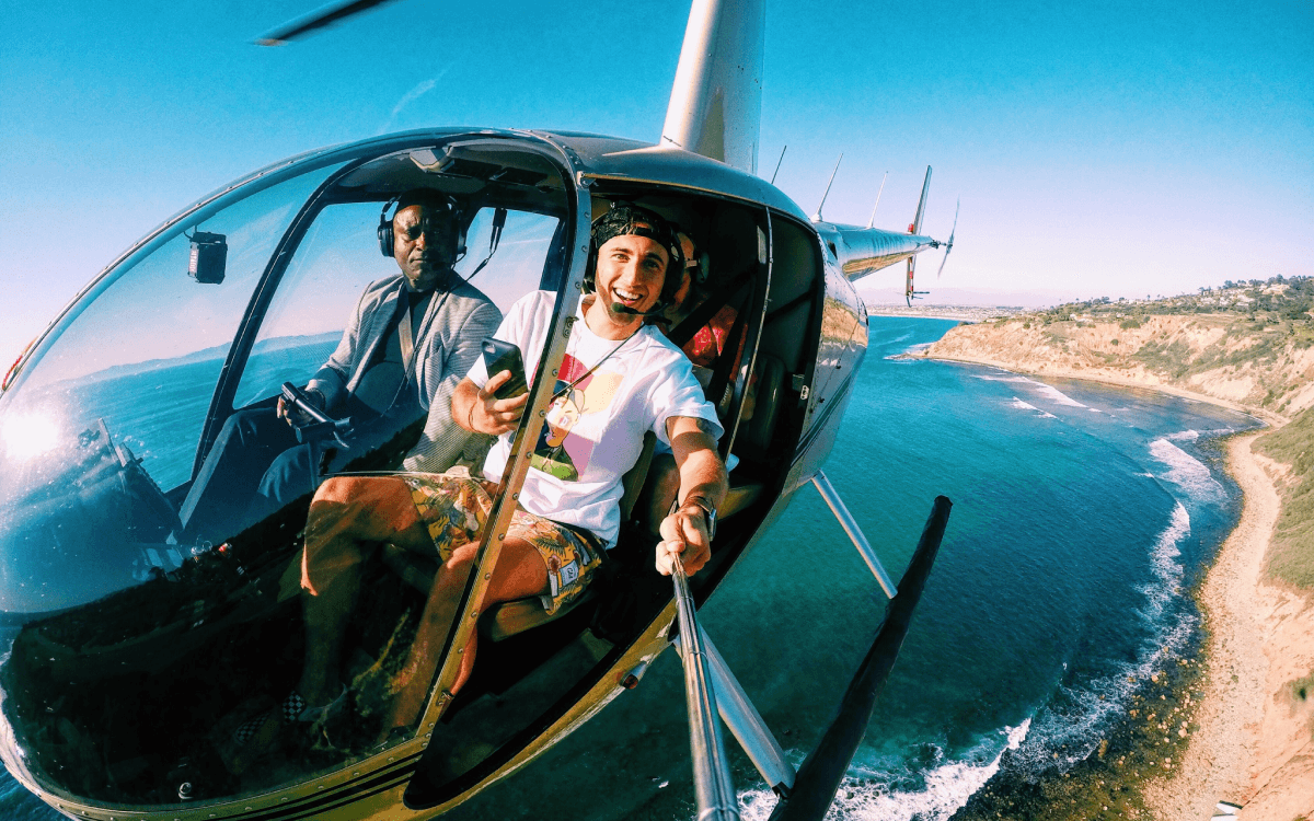Passenger taking a photo with a selfie stick while helicopter above the coast of LA