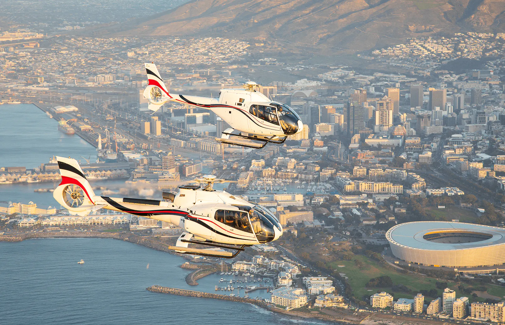 Helicopters flying above the city of Cape Town with the Cape Town stadium in the Background