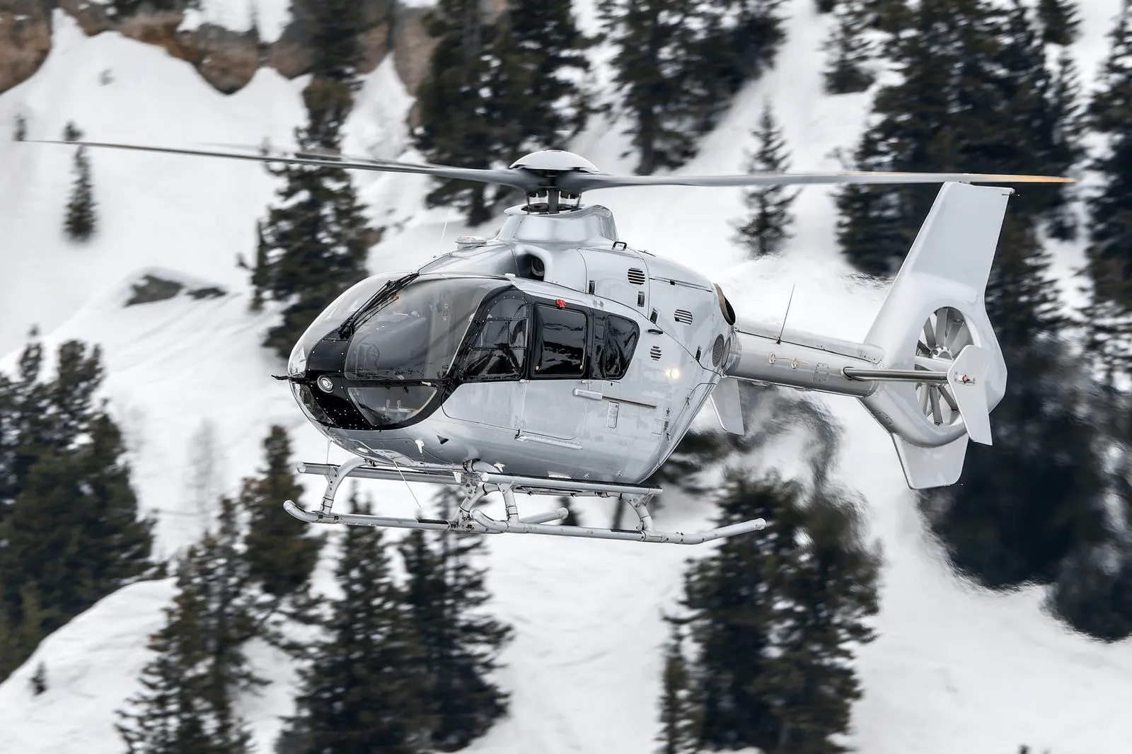 Air Bus H135 flying above snowy mountains