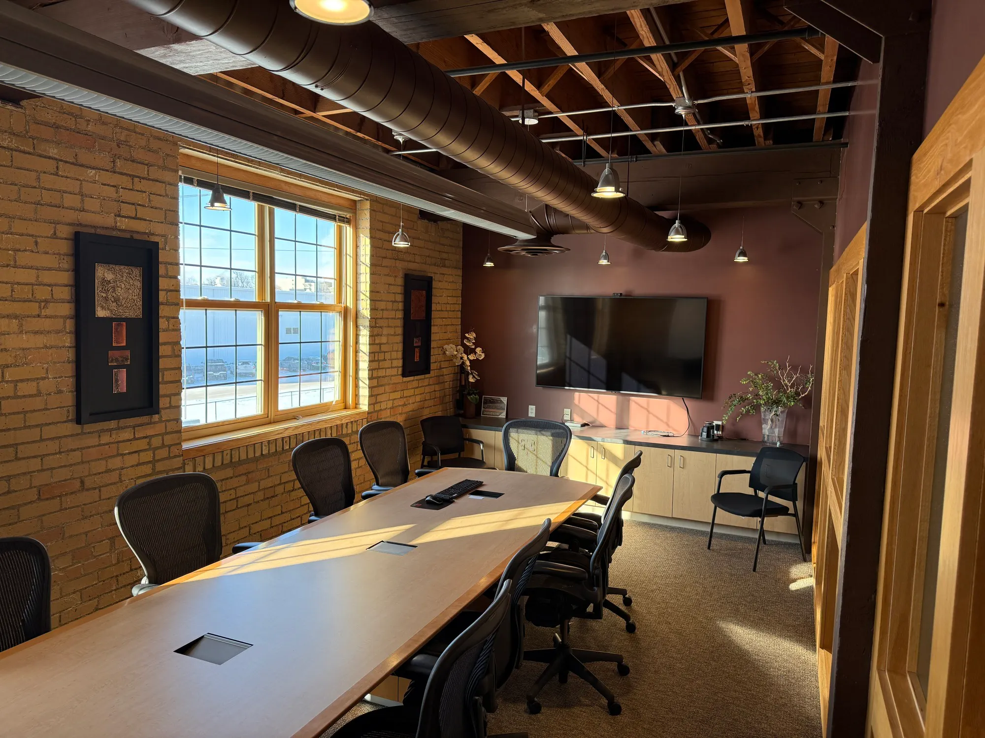 Conference room with exposed brick walls and timber ceiling at the Meadowlark Building