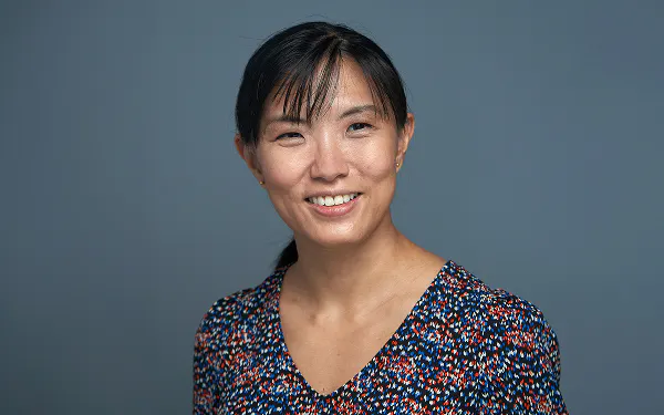 Dr Si-Hui Tan smiling against a blue-grey backdrop