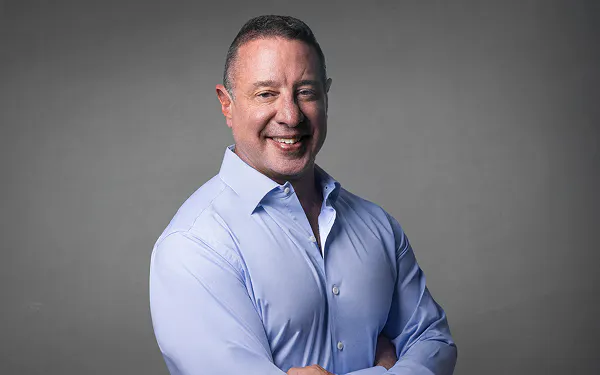 Gregory Gould smiling against a grey backdrop