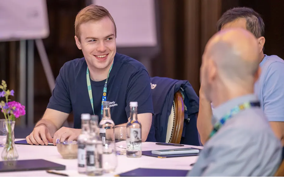 A Horizon team member sits at a banquet table, laughing at another team member whose back is to the camera.