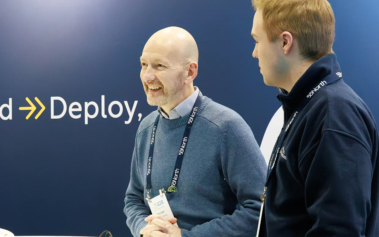 A Horizon team member laughs, looking at something off-camera. He's standing in front of a banner with an error pointing toward the word "Deploy," which is advertising Triple Alpha's core capabilities.  