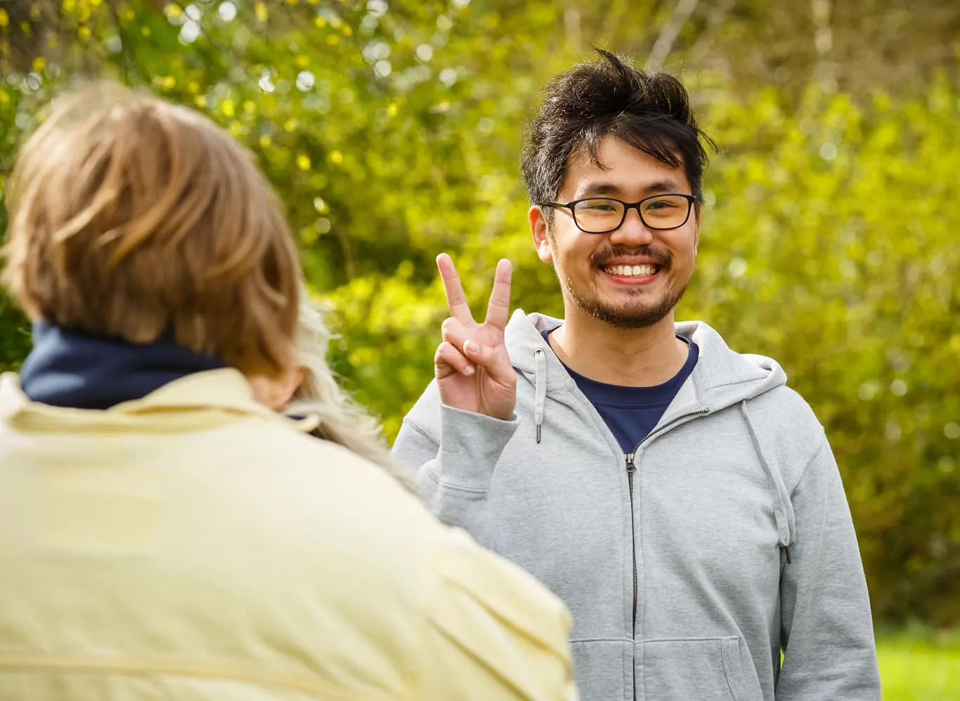 A Horizon Quantum team member smiling and holding up the peace sign. He is standing outside in front of a lot of greenery at the Horizon offsite in Ireland