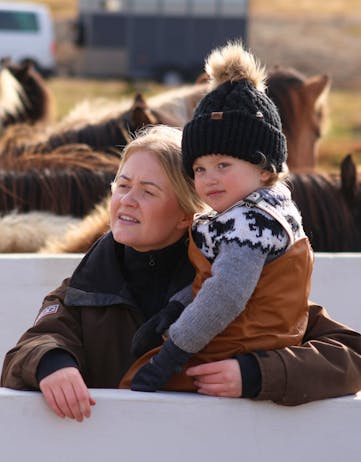 A mother a child watching horse roundups in Iceland