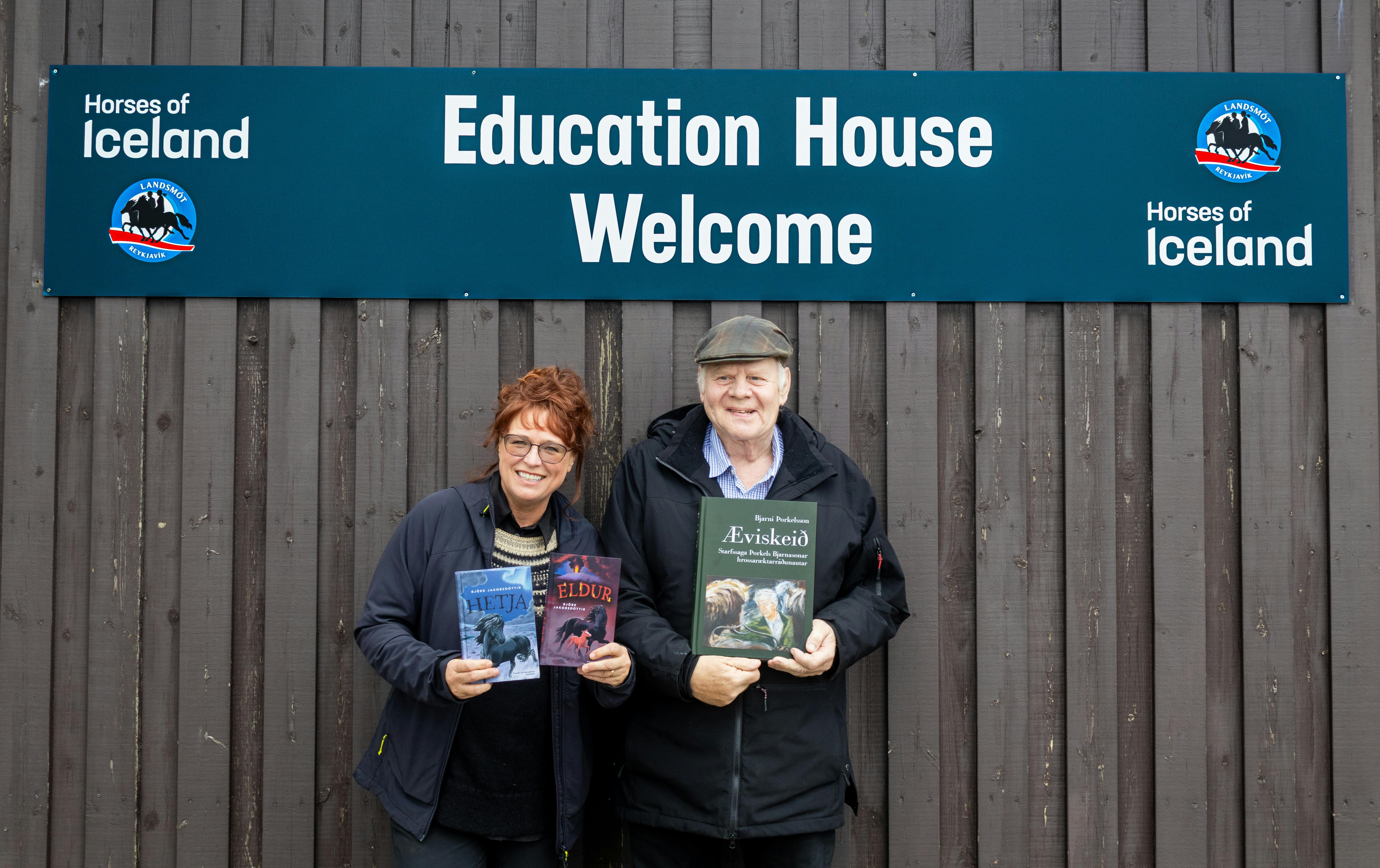 Björk Jakobsdóttir and Bjarni Þorkelsson hold their books Hetja, Eldur and Æviskeið in front og them byt the Education House at Landsmót