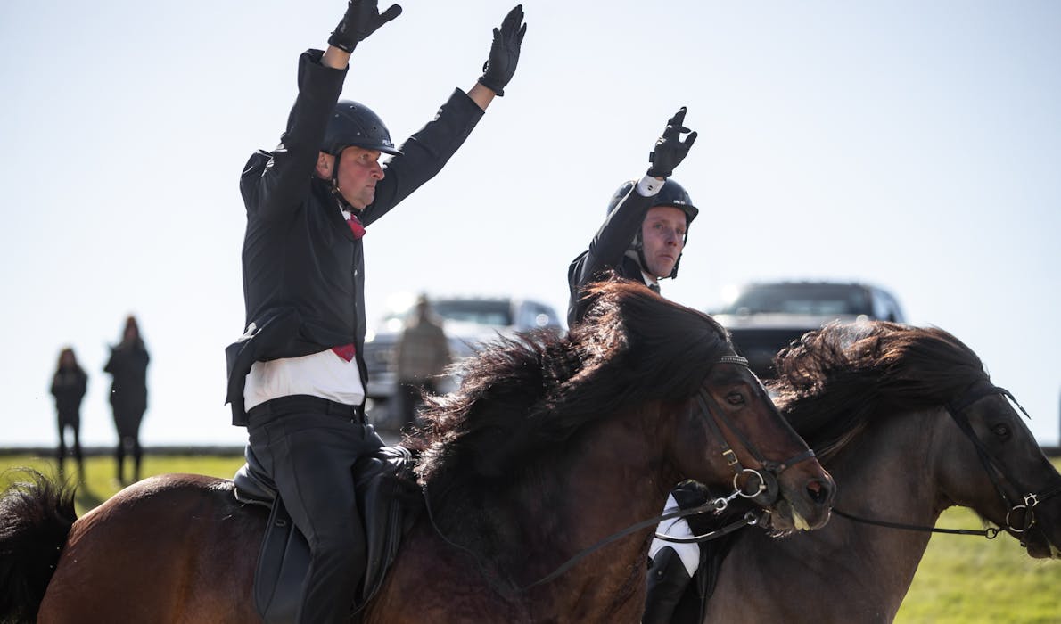Sigurður Vignir Matthíasson and Sigursteinn Sumarliðason ride side by side and raise their arms in Pace during Landsmót 2024