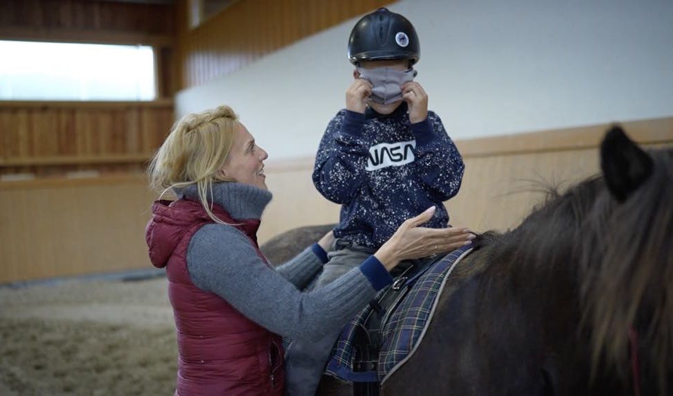 Eva András giving a riding lesson to a child on an Icelandic horse