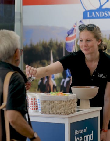 Berglind Margo Þorvaldsdóttir, our project manager, hands over a magnet to a guest at the Horses of Iceland stand at the World Championships in Birmenstorf.