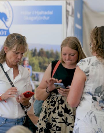 Women on their phone to participate to Horses of Iceland's raffle during the World Championships.