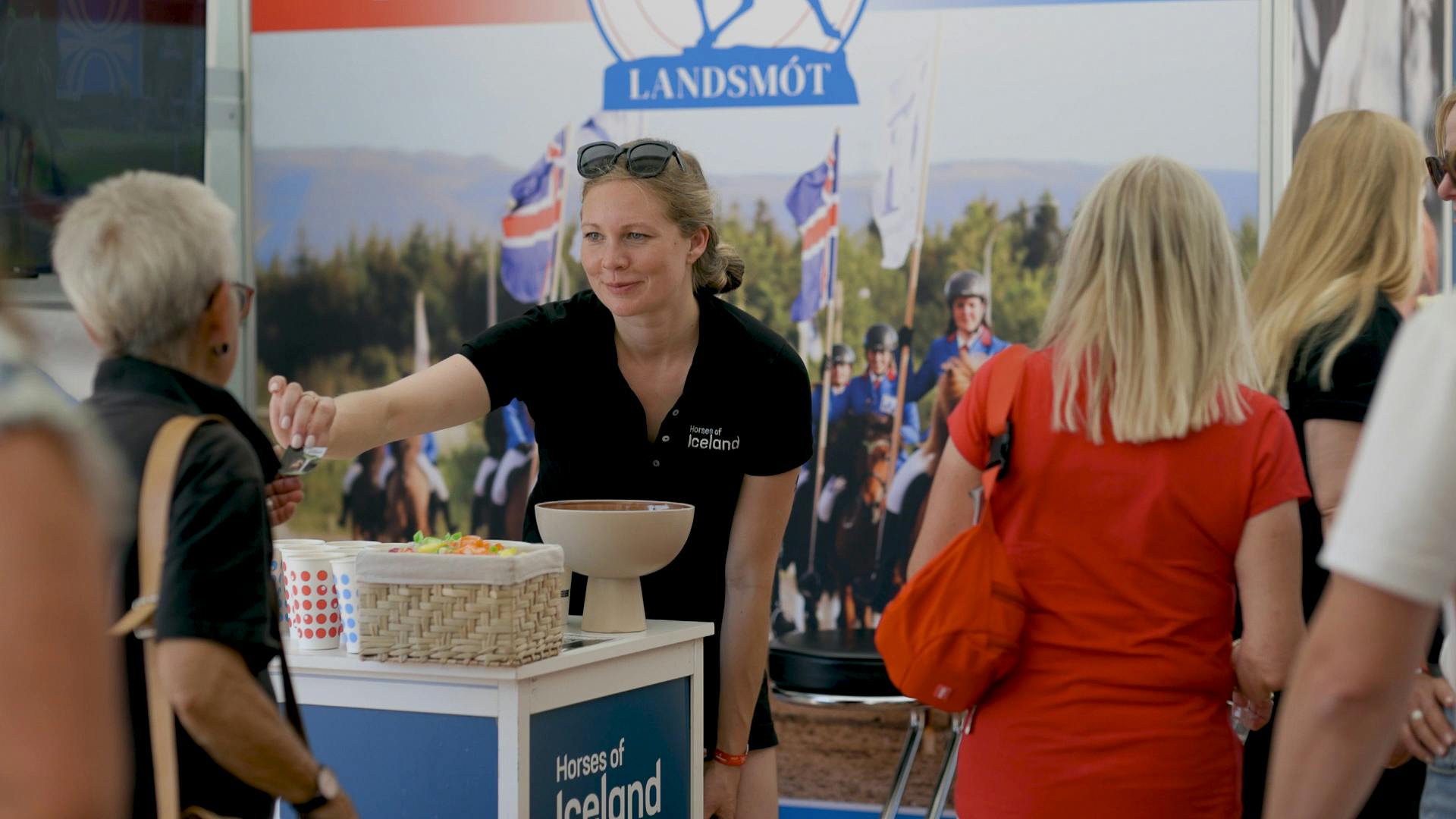 Berglind Margo hands over a magnet at the Landsmót stand at the World Championship for Icelandic horses in Switzerland, 2025