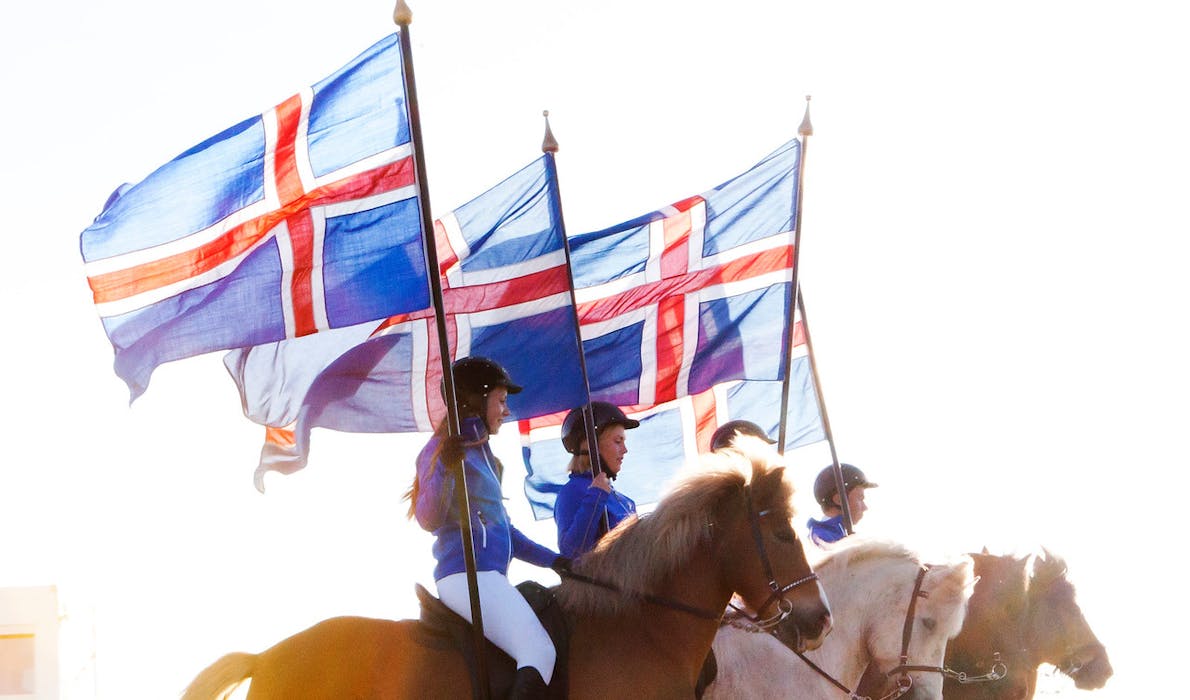 Icelandic horses and riders with the Icelandic flag at Landsmót, 2022