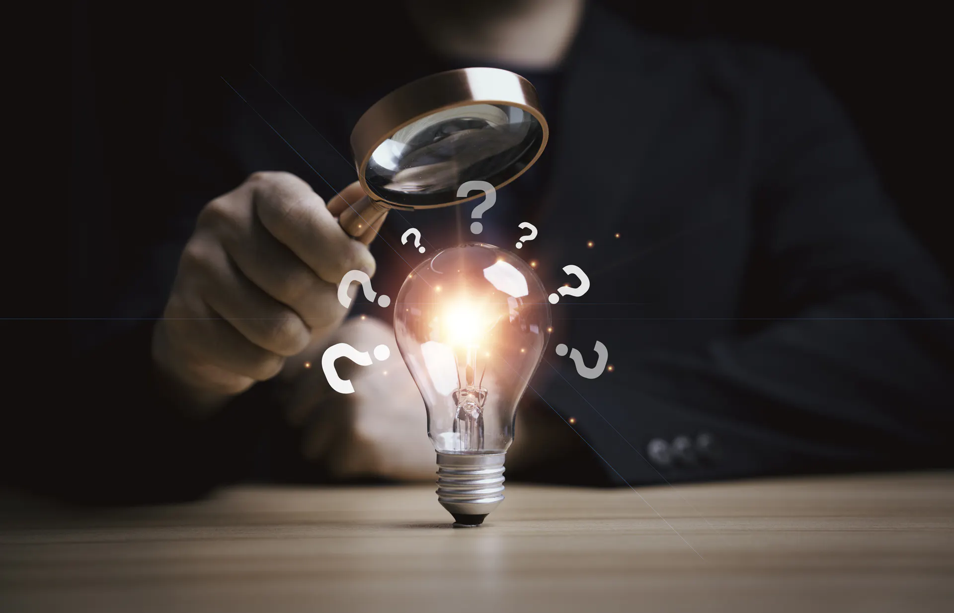 Man holding a magnifying glass to a lightbulb