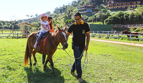 Criança acompanhada de um adulto em um passeio a cavalo