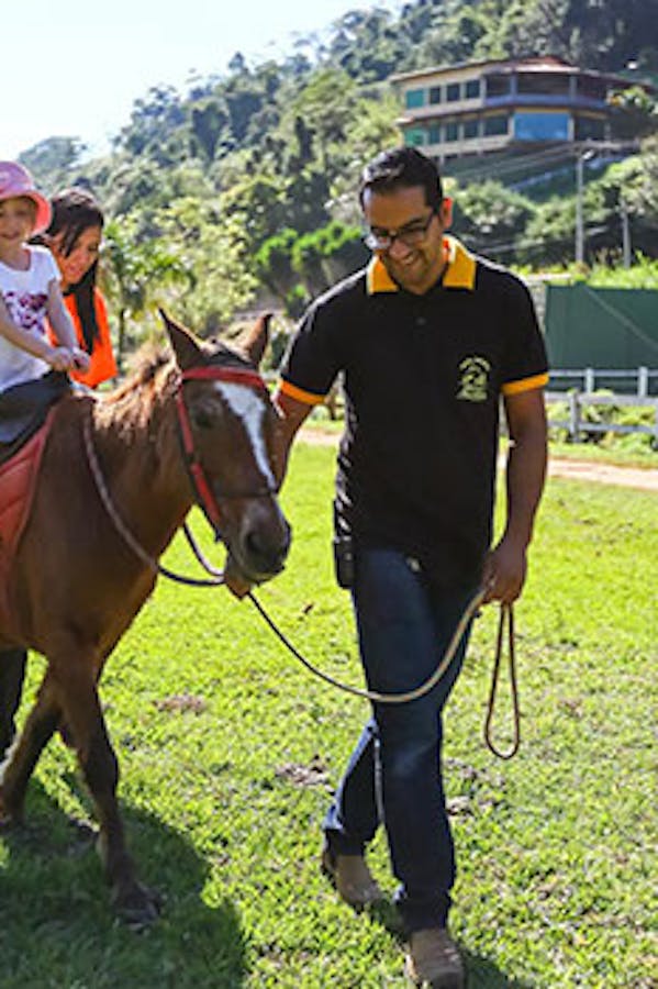 Criança acompanhada de um adulto em um passeio a cavalo