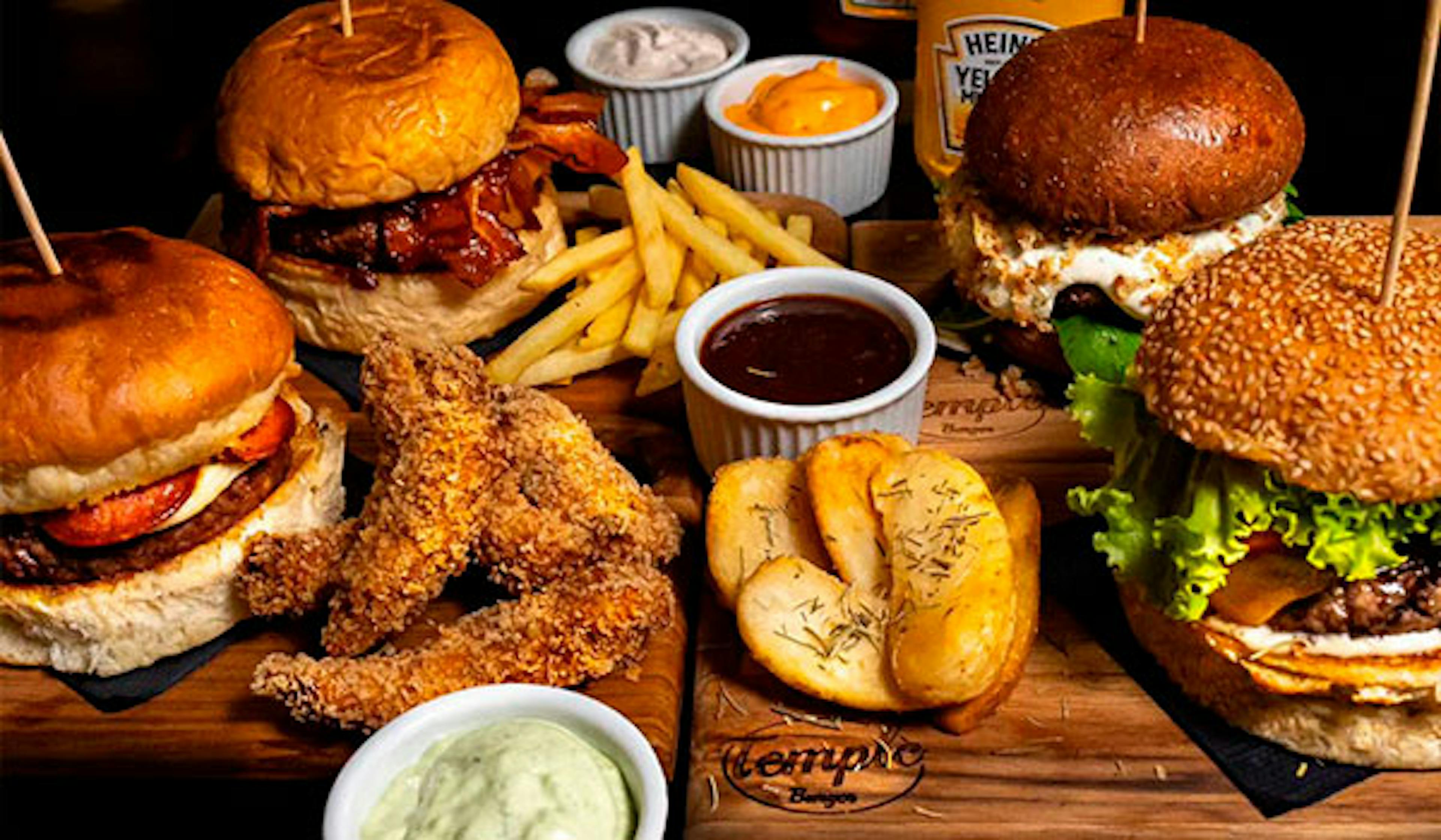 Mesa repleta de hamburguer e batatas