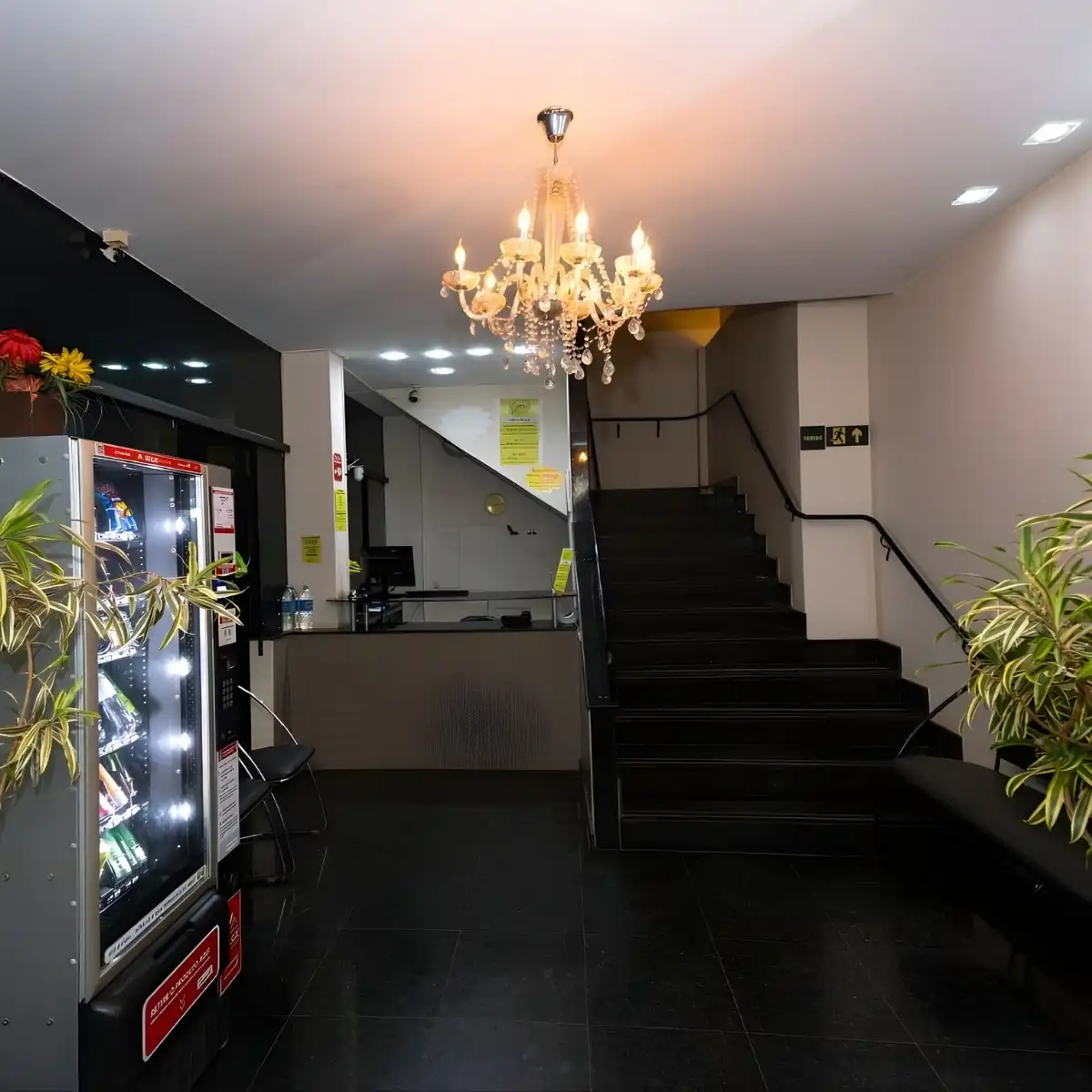 Interior de um hall de entrada de um prédio ou hotel com escada, luminária de cristal e vending machine na decoração moderna.