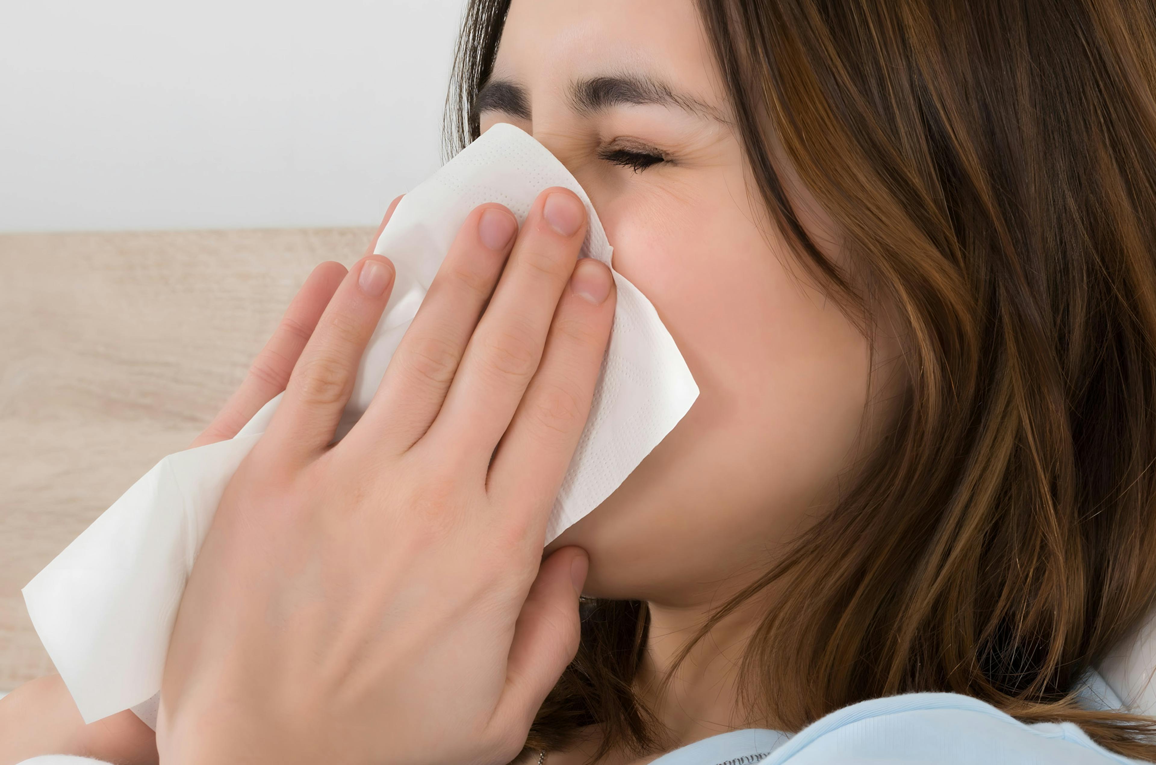 A woman in blowing her nose in need for hayfever treatment
