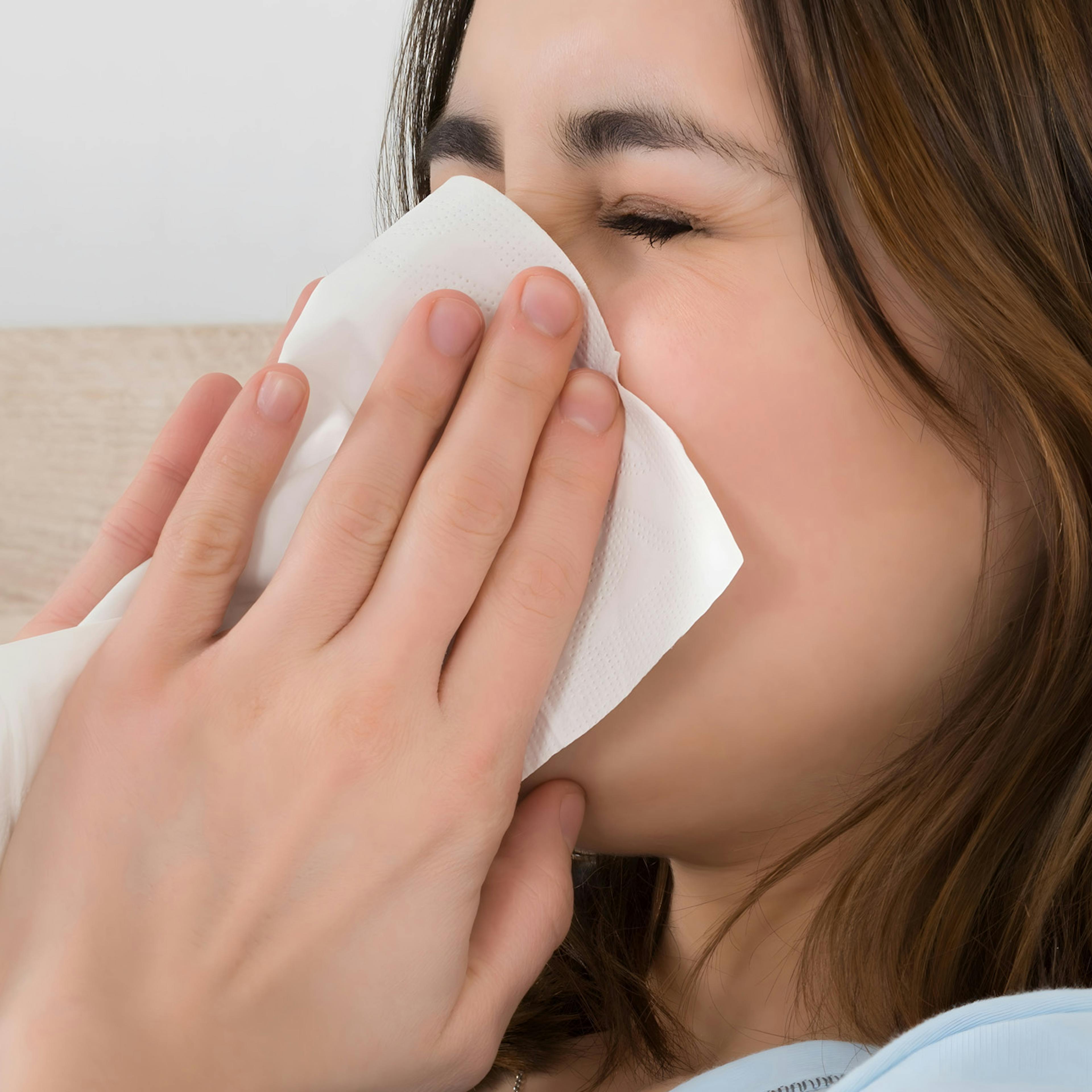 Woman blowing her nose - representing hayfever treatment