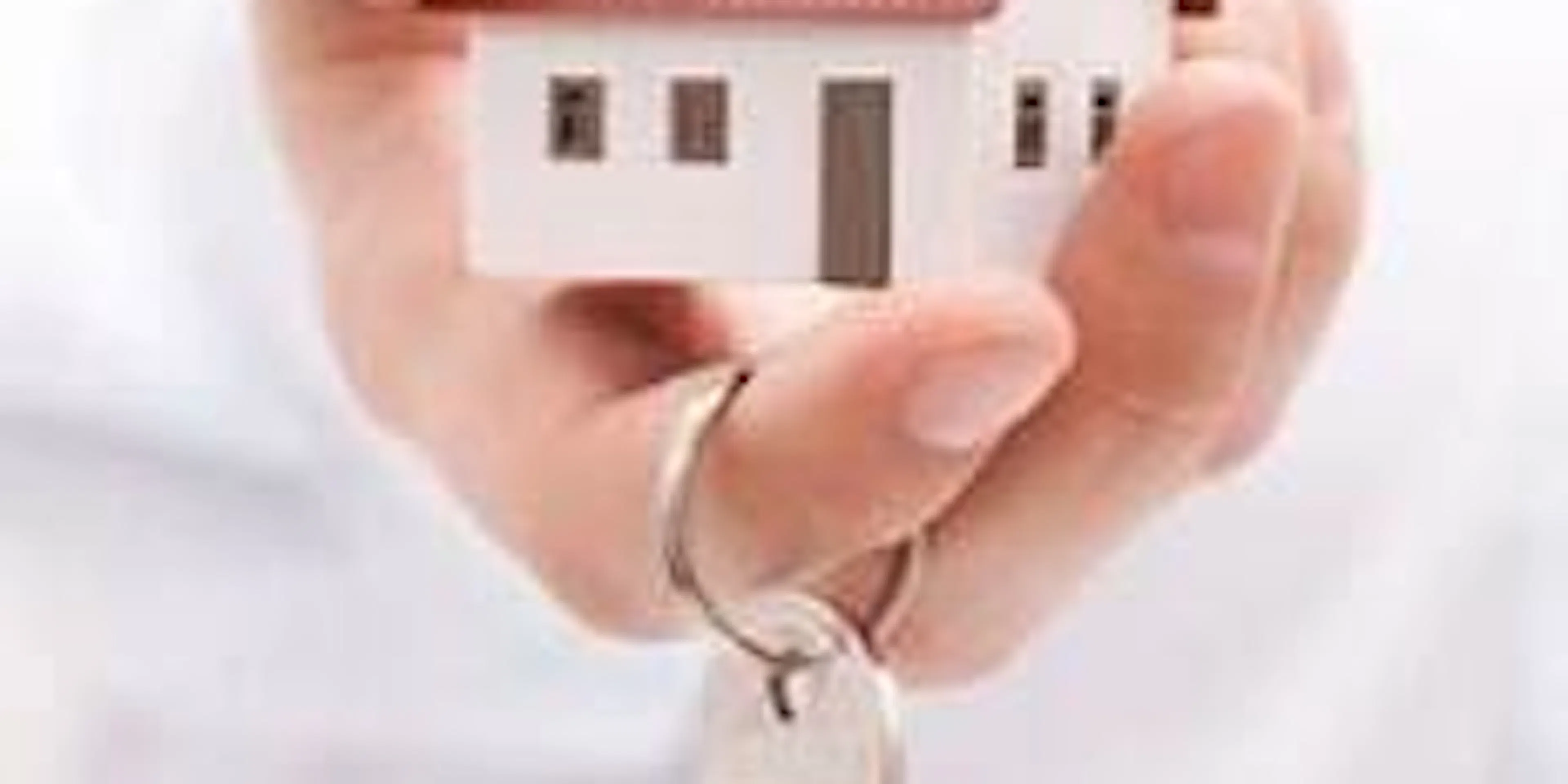 Une main tenant une miniature de maison et une clé