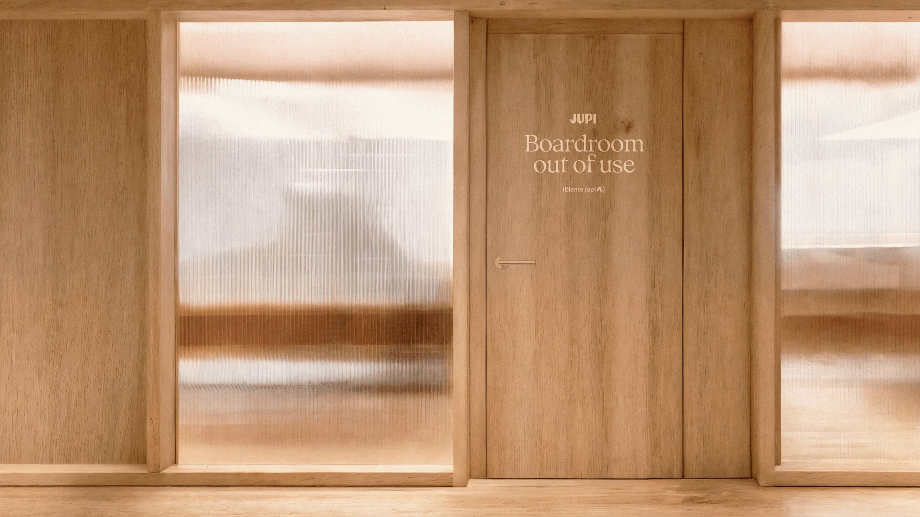 Wooden boardroom door with a Jupi sign reading 'Boardroom out of use'