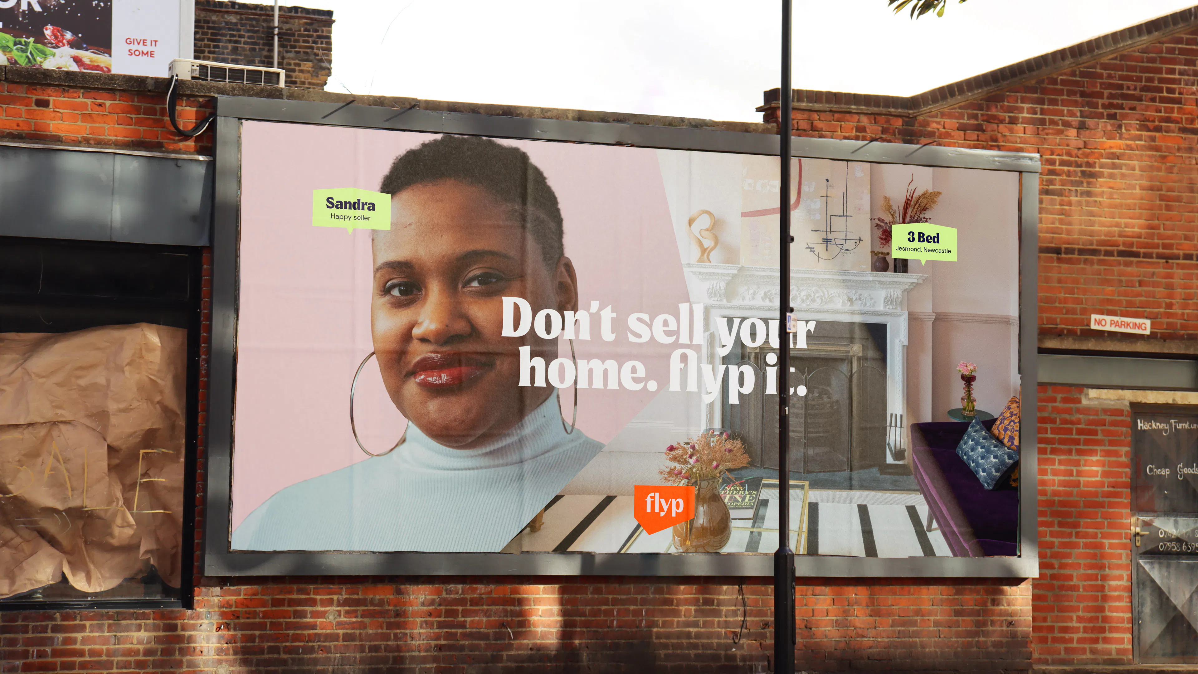 Roadside billboard reading 'Don't sell your home. flyp it.' with a portrait of a woman beside a living room