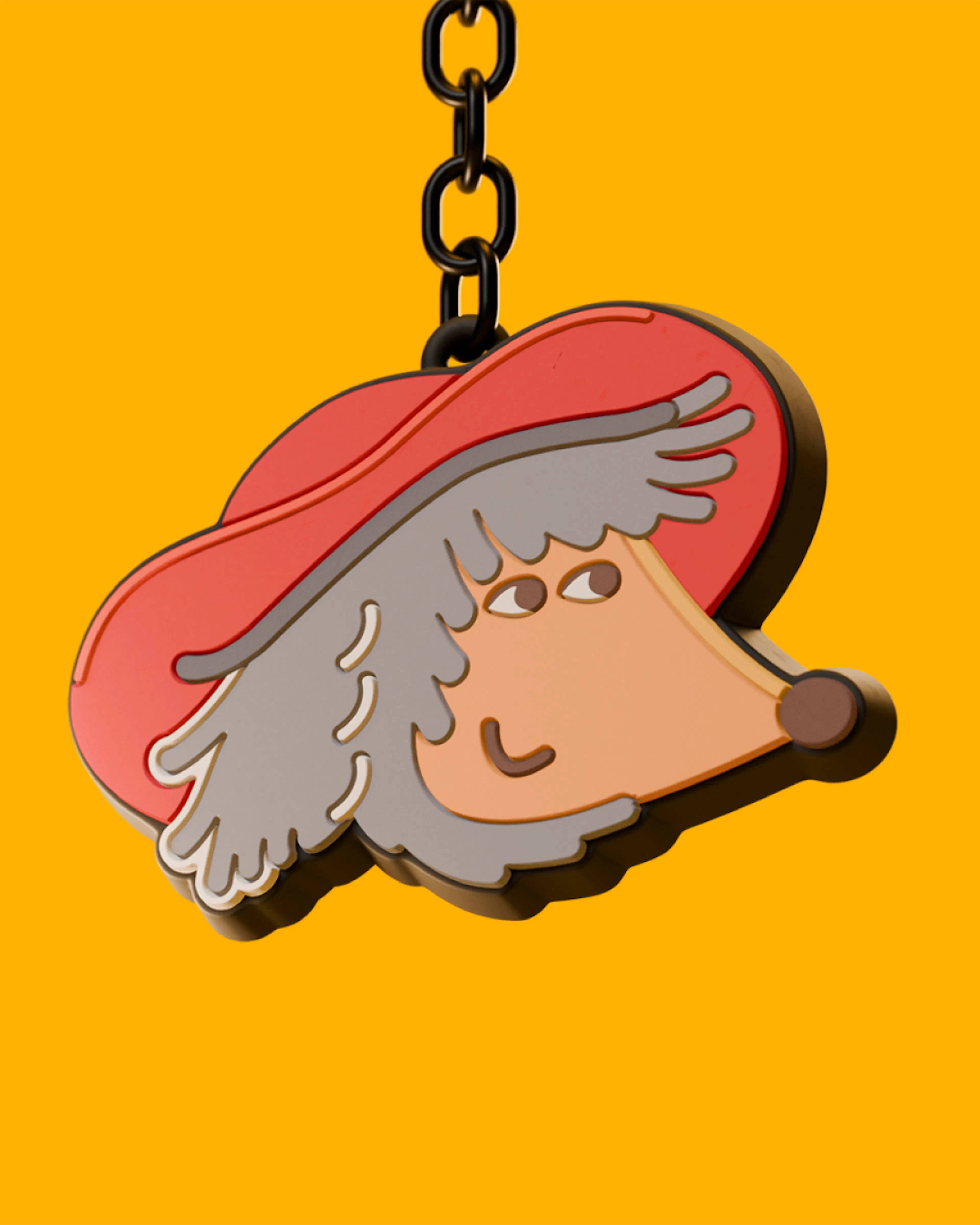 An enamel keyring of Orinoco’s face in his red hat, hanging from a chain against a yellow background