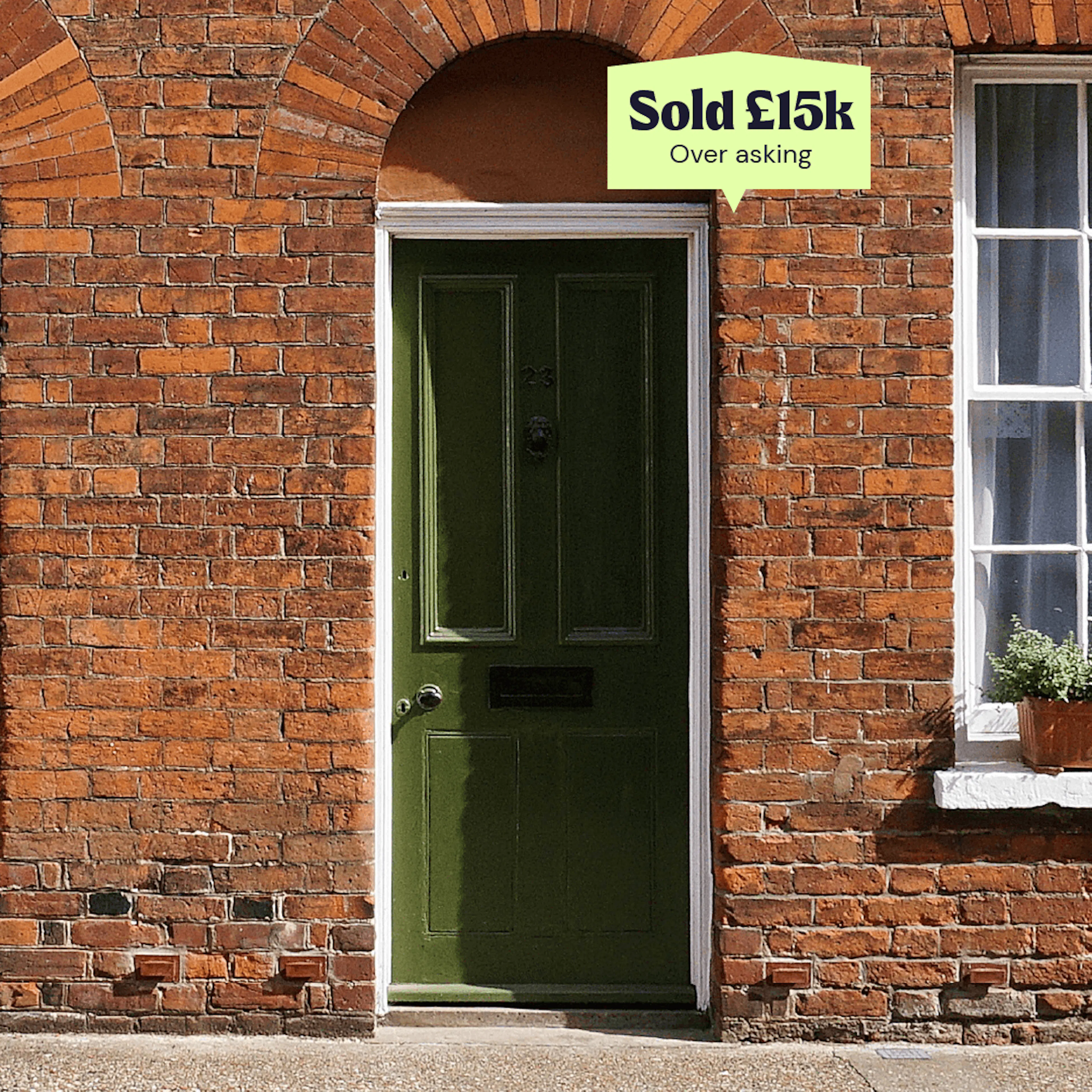 Brick house with a green front door and a lime flyp 'Sold' sign above it