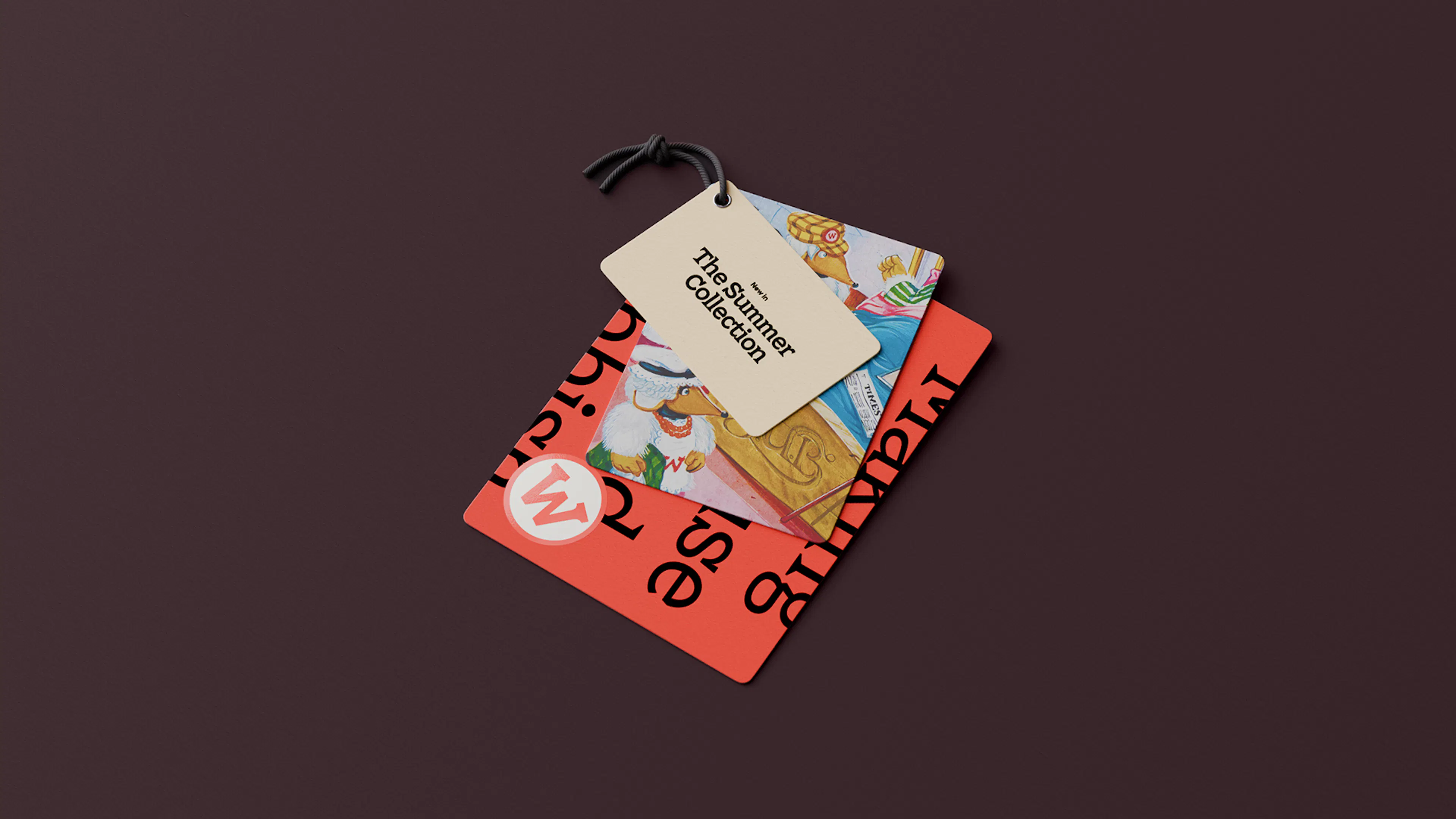 Layered Wombles swing tags on a dark plum background, a cream tag reading ‘The Summer Collection’ over a red tag with the W logo and Womble illustrations