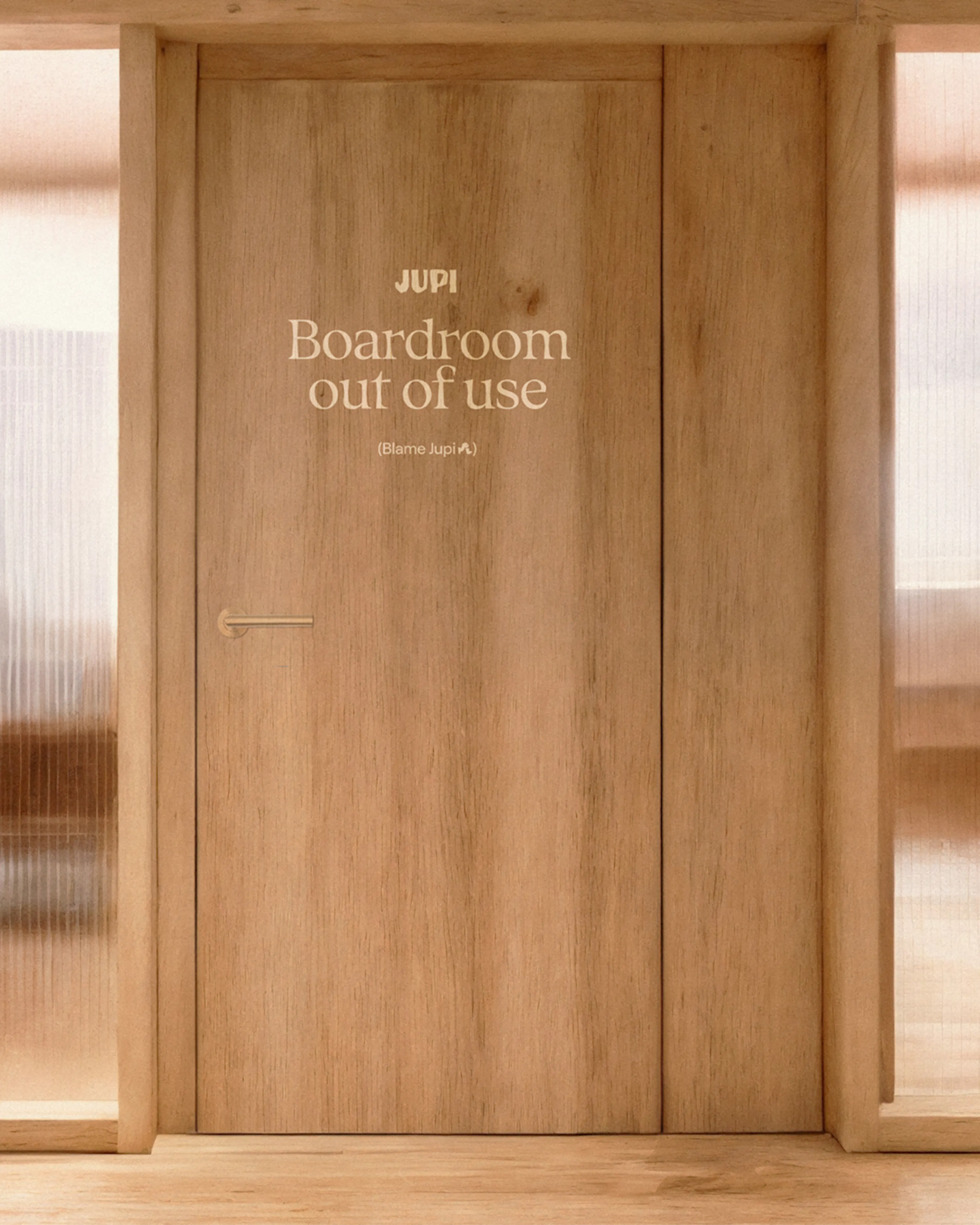 Wooden boardroom door with a Jupi sign reading 'Boardroom out of use'